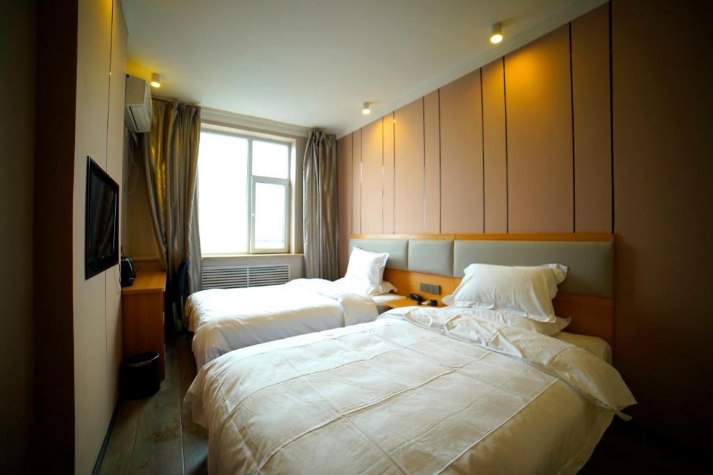 太原市にあるJUN Hotels Shanxi Taiyuan Gaoxin Communityのベッド2台と窓が備わるホテルルームです。