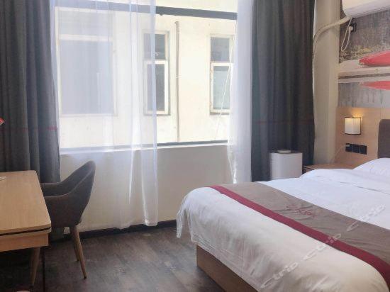 a hotel room with a bed and a window at Thank Inn Plus Hotel Yichang Free Trade Zone Development Avenue in Yichang