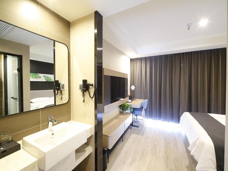 a hotel room with a bed and a sink and a mirror at Up And In Anhui Huainan Tianjiaan District Hualian Commercial Building in Huainan