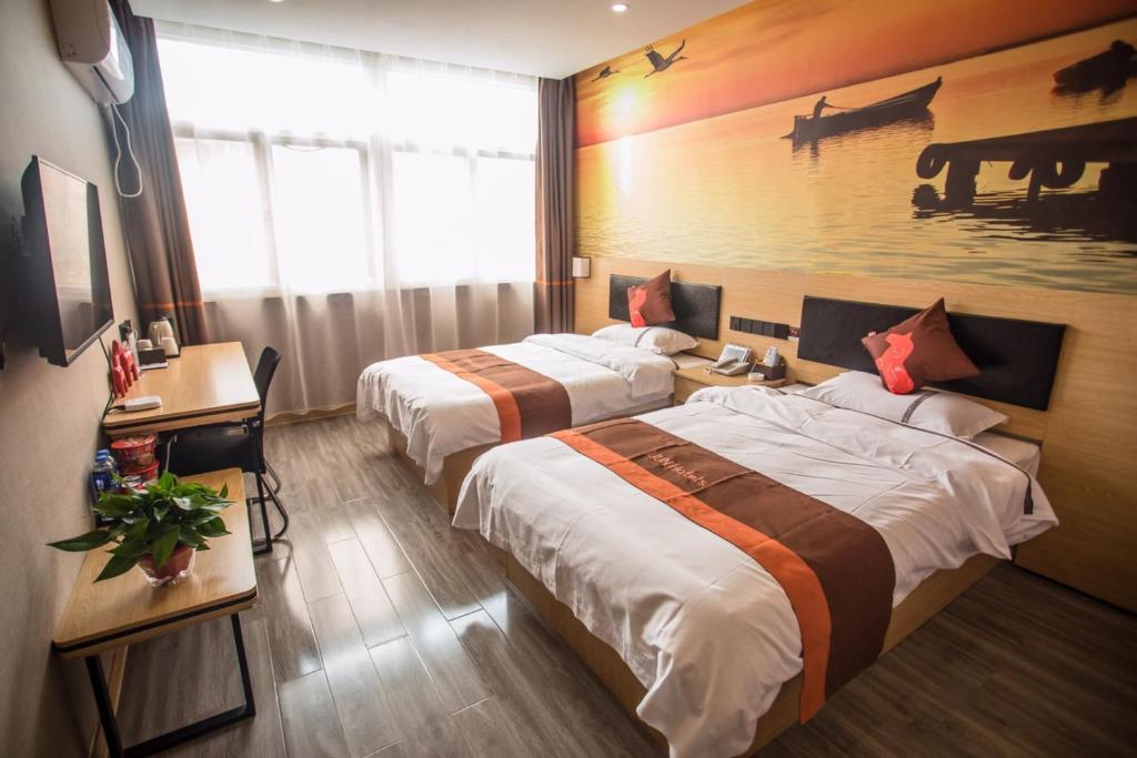 a hotel room with two beds and a painting on the wall at JUN Hotels Hebei Xingtai Qinghe County Bohai Road in Huangjinzhuang