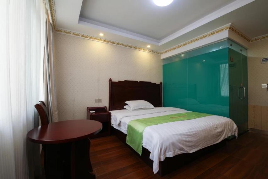 a bedroom with a bed and a table in it at JUN Hotels Guangdong Shenzhen Yantian District Zhongying Street in Shenzhen