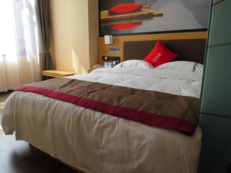 - une chambre avec un grand lit et des oreillers rouges dans l'établissement Thank Inn Chain Hotel Yunnan Dali Yunlong County Caojian Town Wanghuan Road, à Caojian