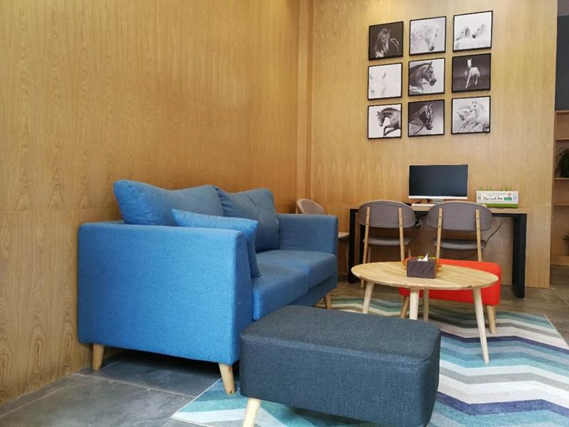 a living room with a blue couch and a table at JUN Hotels Guizhou Tongren Jiangkou County Fanjingshan Store in Tongren