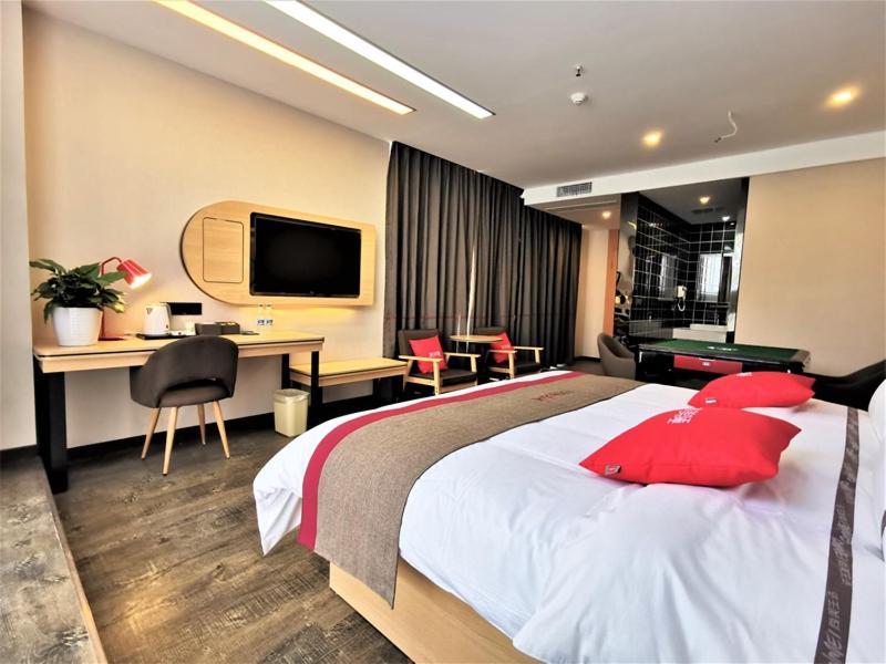 um quarto de hotel com uma cama grande com almofadas vermelhas em Thank Inn Chain Hotel Guangan Huaying Phoenix City em Shuang-ho