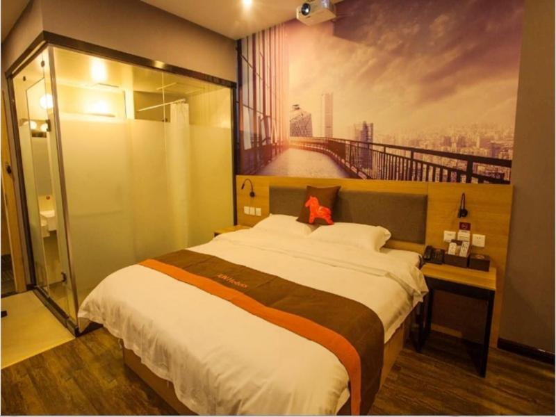 a bedroom with a large bed with a painting on the wall at JUN Hotels Hebei Hengshui Taocheng District Heping West Road in Hengshui