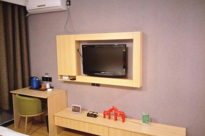 a room with a tv on a wall with a table at JUN Hotels Hebei Hengshui Shenzhou Bus Station in Hengshui