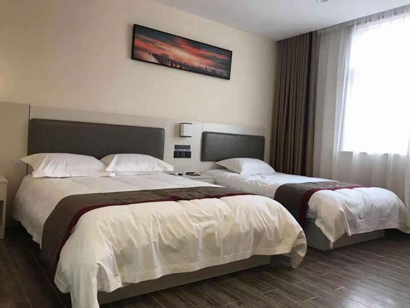 a hotel room with two beds and a window at Thank Inn Chain Hotel Shandong Laiwu Laicheng District Changshou North Road People's Hospital in Laiwu