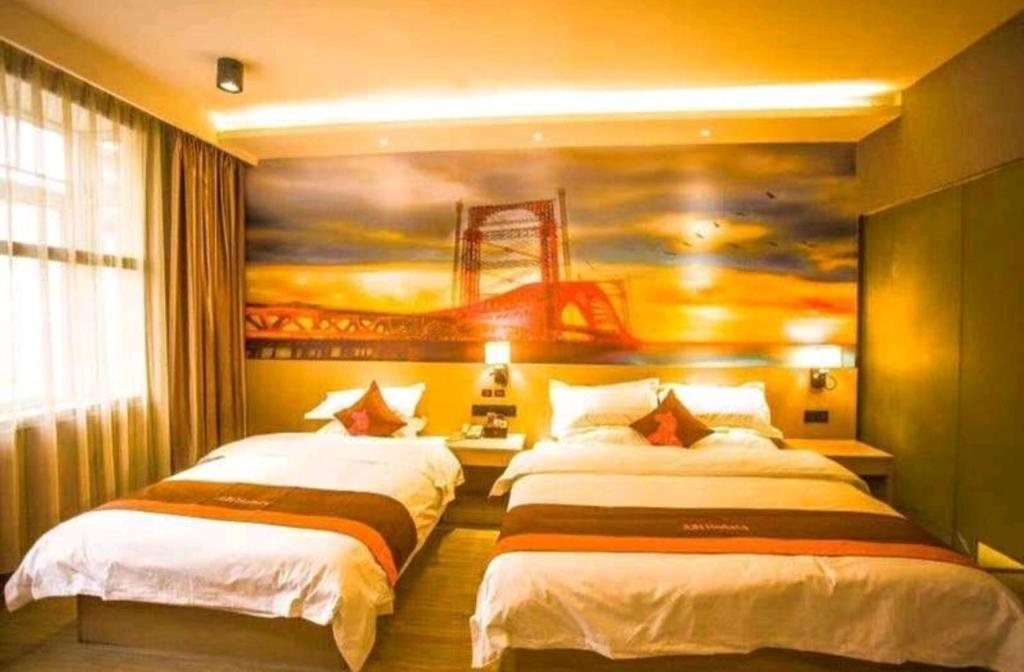 duas camas num quarto com um quadro na parede em JUN Hotels Liuzhou Sanjiang County Dongxiang Avenue em Sanjiang