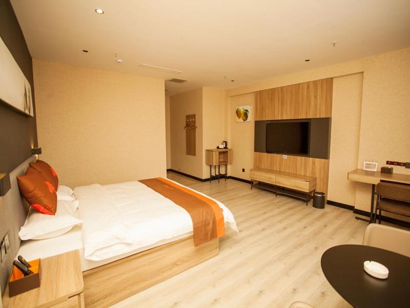 石家荘市にあるJUN Hotels Hebei Shijiazhuang Wuji County Zhengyi Street Storeの大きなベッドとデスクが備わるホテルルームです。