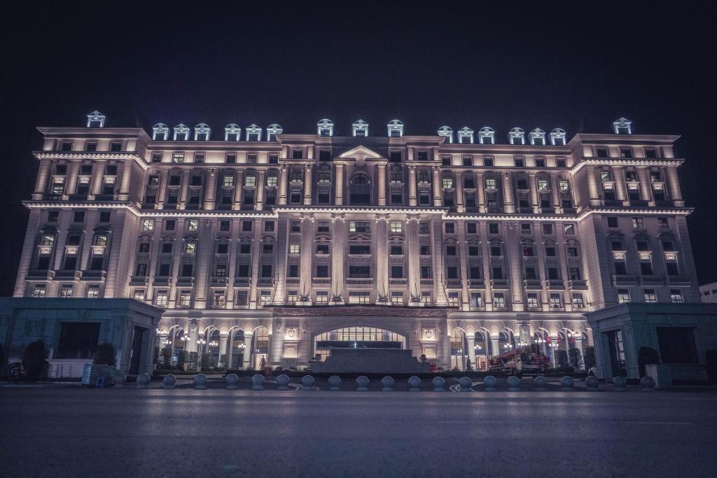 Un grand bâtiment est éclairé la nuit. dans l'établissement Taizhou Haiyan Jinling International Hotel, à Taizhou