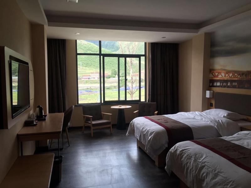 Habitación de hotel con 2 camas, escritorio y ventana en Thank Inn Chain Hotel Ganzi Kangding City Xinduqiao, en Garze