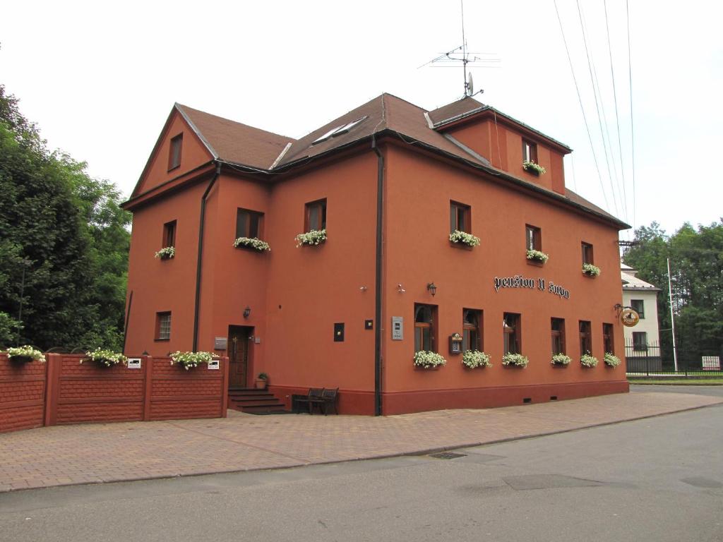 Un grand bâtiment orange avec des fleurs dans les fenêtres dans l'établissement Penzion Vulture Havířov, à Havířov