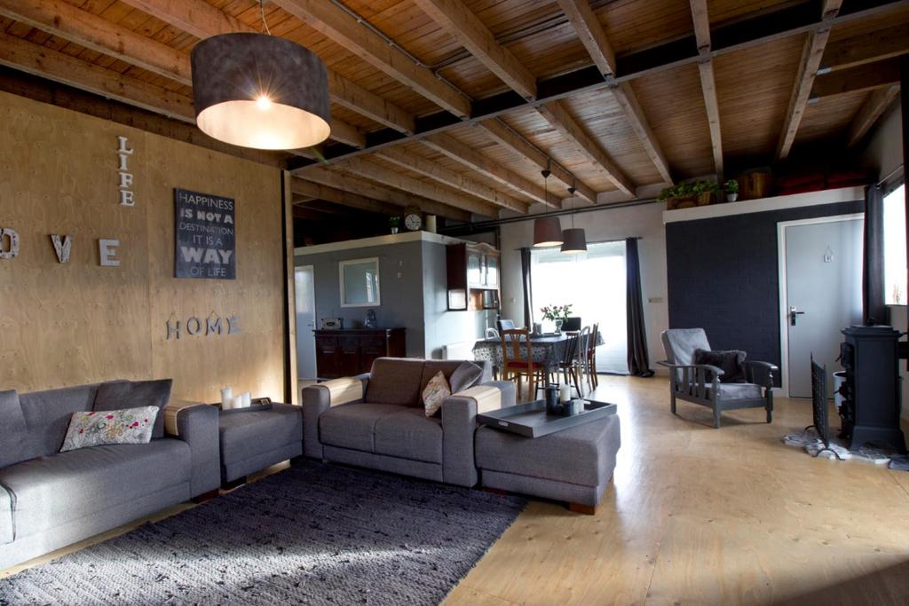 una sala de estar con sofás y una mesa en una habitación en Boerderij de Zalm en Schalkwijk