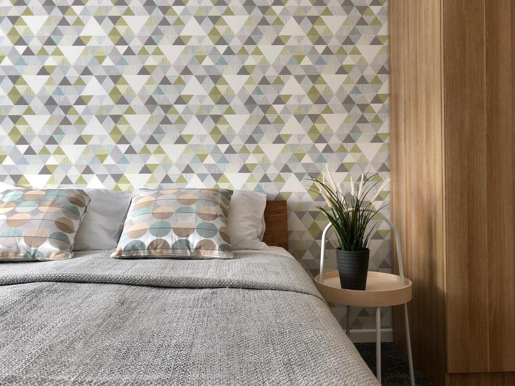 a bedroom with a bed with a geometric wall at COMFY Patogūs namai in Kaunas