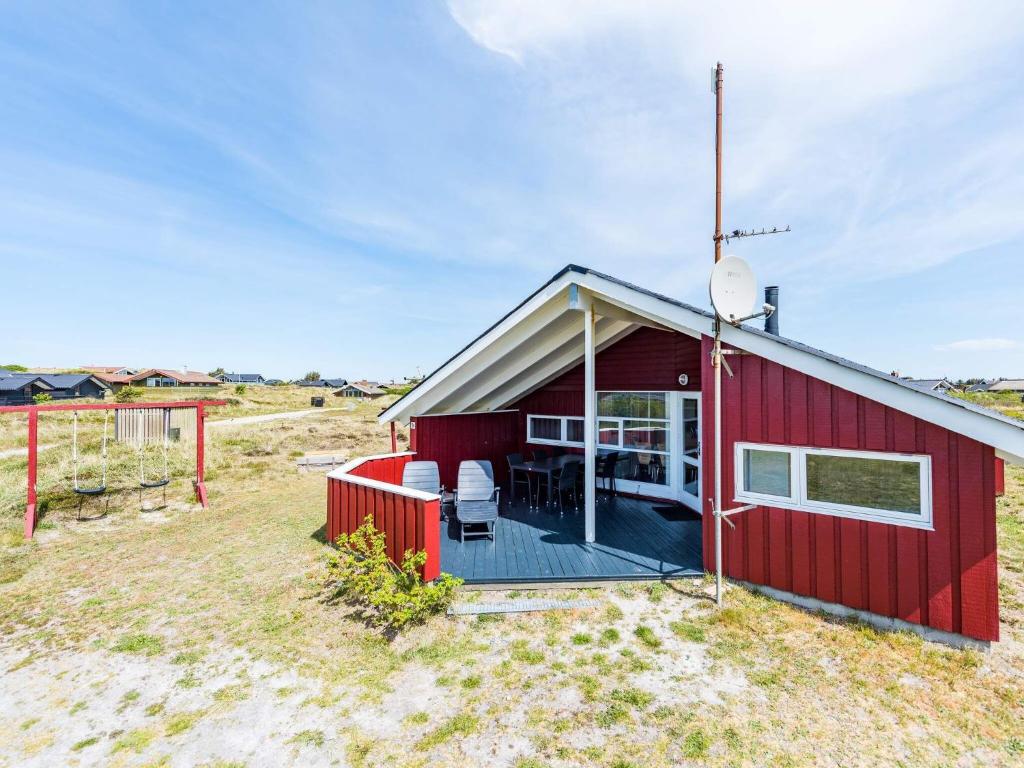 une maison rouge avec une terrasse et une télévision par satellite dans l'établissement Holiday home Hvide Sande LXIV, à Havrvig