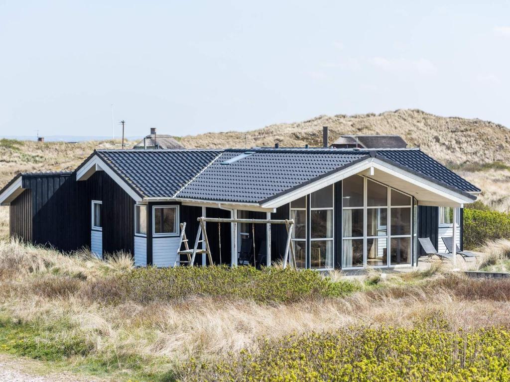 una casa negra con paneles solares. en Holiday home Hvide Sande LXXII, en Hvide Sande