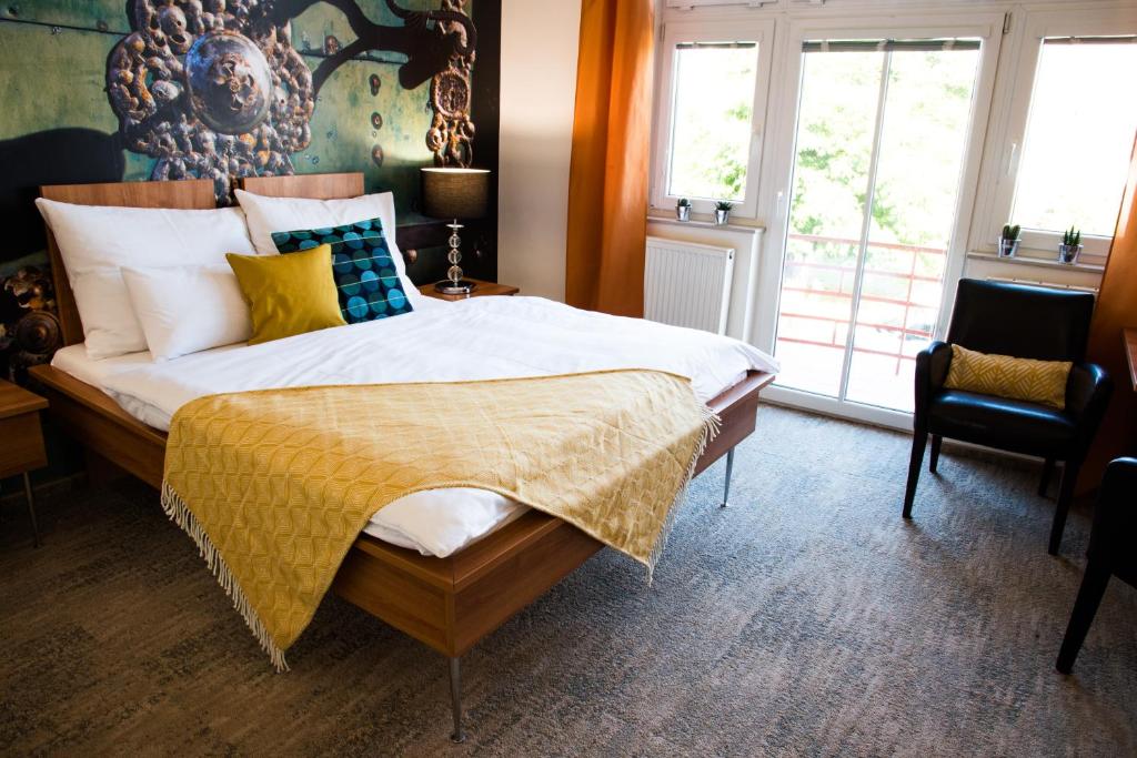 a bedroom with a large bed with yellow and blue pillows at Boutique Hotel Golf Garni in Mikulov