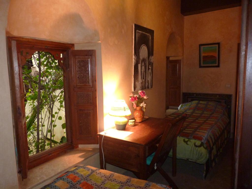 una camera da letto con tavolo, letto e finestra di Riad Marlinea a Salé