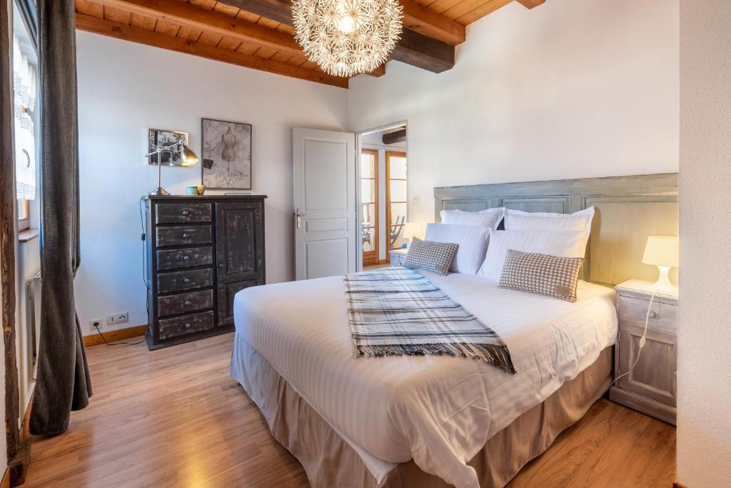 a bedroom with a large bed and a chandelier at La Cour St-Fulrad - Les Suites in Saint-Hippolyte