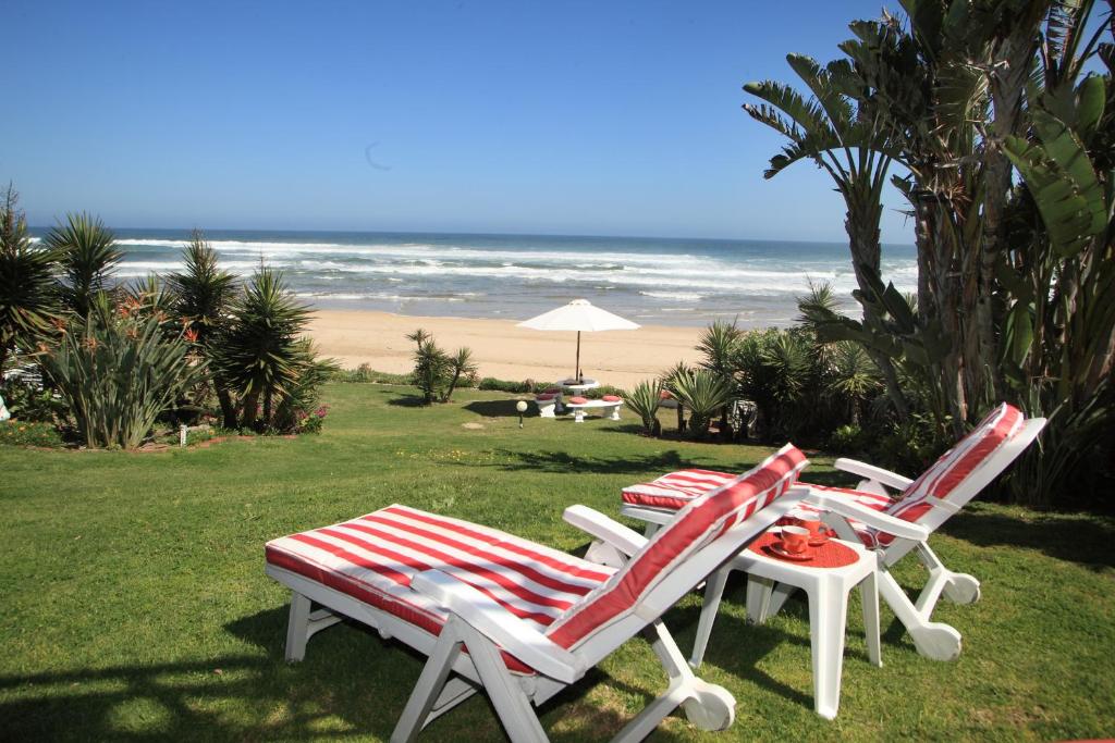 two lawn chairs and a table with a view of the beach at Haus am Strand - on the Beach in Wilderness