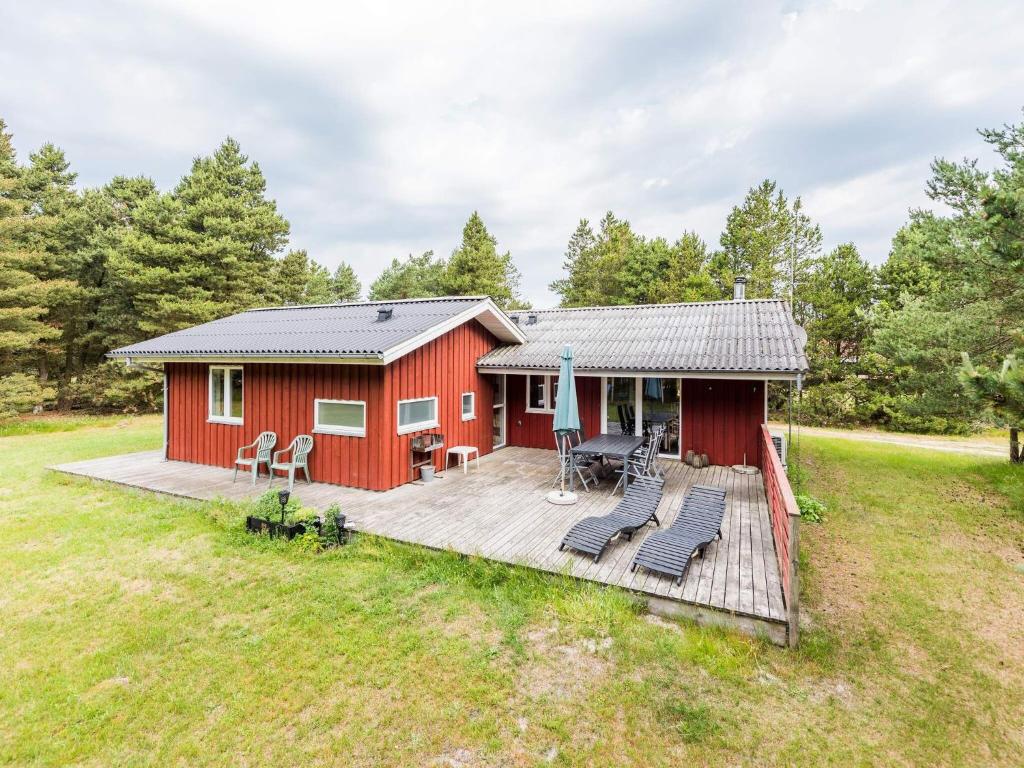cabina roja con terraza en un campo en Holiday home Blåvand CXCIII, en Blåvand