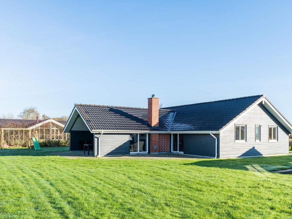 a house with a large grass field in front of it at Tranquil Cottage with Spa and Sauna-By Traum in Hemmet