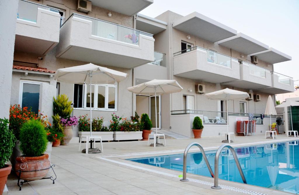 a villa with a swimming pool in front of a building at Christina Hotel in Adelianos Kampos