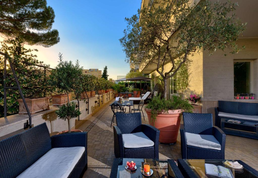 um pátio exterior com cadeiras, mesas e árvores em Best Western Hotel Rivoli em Roma