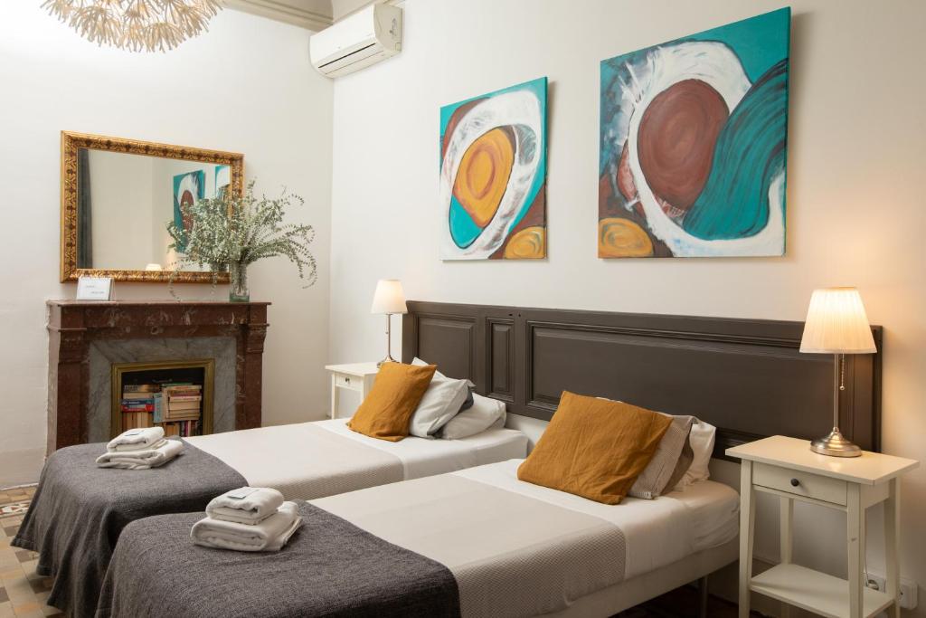 two beds in a room with paintings on the wall at Casa Maca Guest House in Barcelona