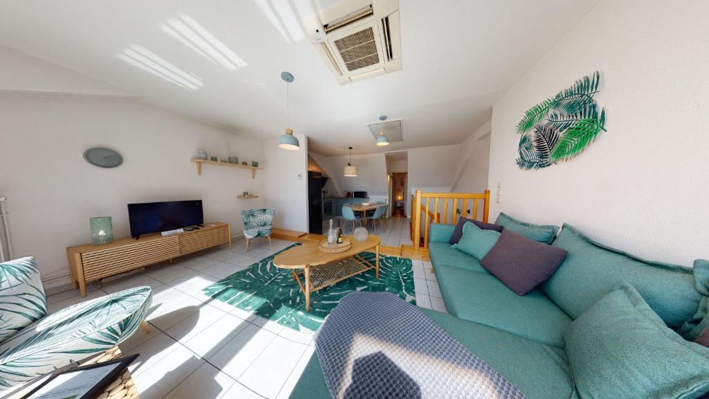ein Wohnzimmer mit einem blauen Sofa und einem Tisch in der Unterkunft Duplex des Dominicains - 1 Parking GRATUIT - Hypercentre 6 personnes in Colmar