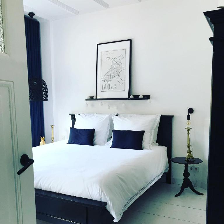 a bedroom with a bed with white sheets and blue pillows at B&B Logeren bij Lies in Harderwijk