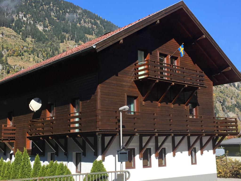 a wooden building with a balcony in front of a mountain at Ski Lodge Jaktman in Bad Gastein