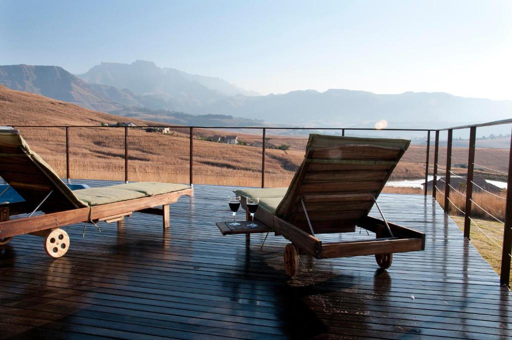 two rocking chairs on a deck with a view of the mountains at Cathkin Haven in Champagne Valley