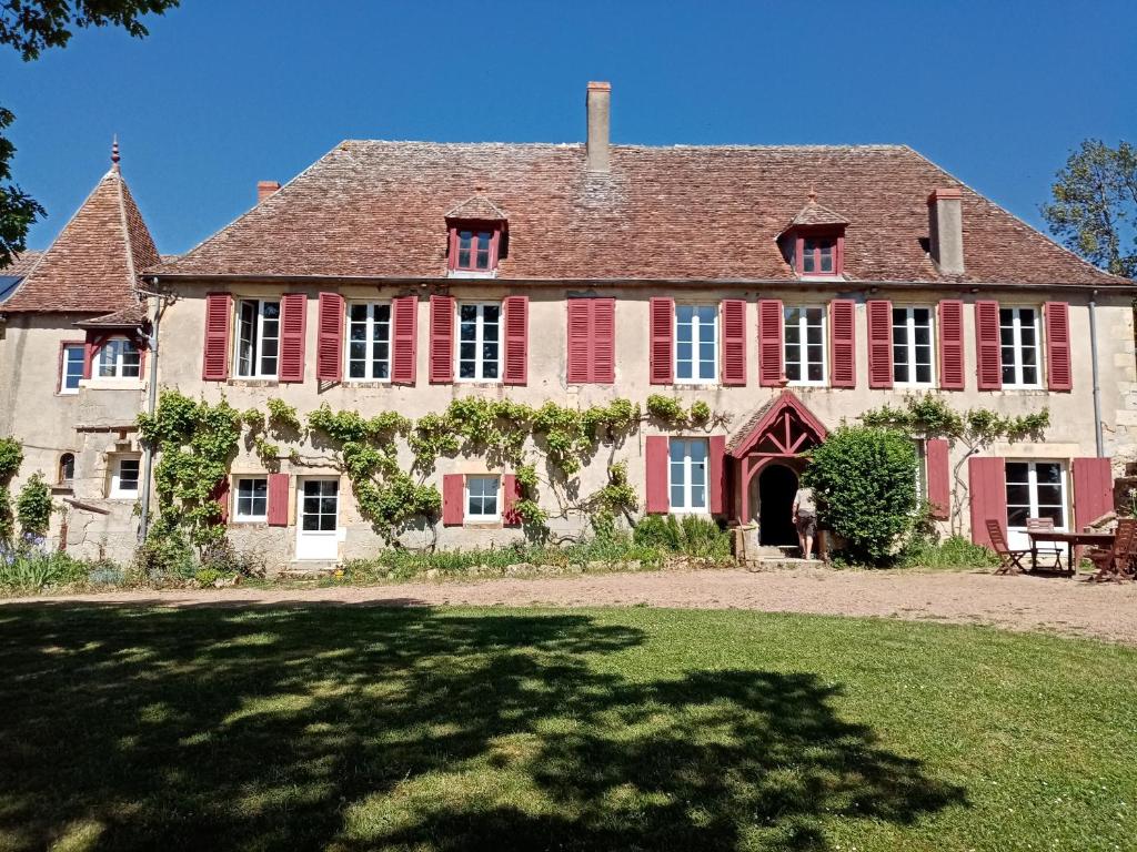 une grande maison avec des fenêtres rouges et une cour dans l'établissement Les Indrins, à Marzy