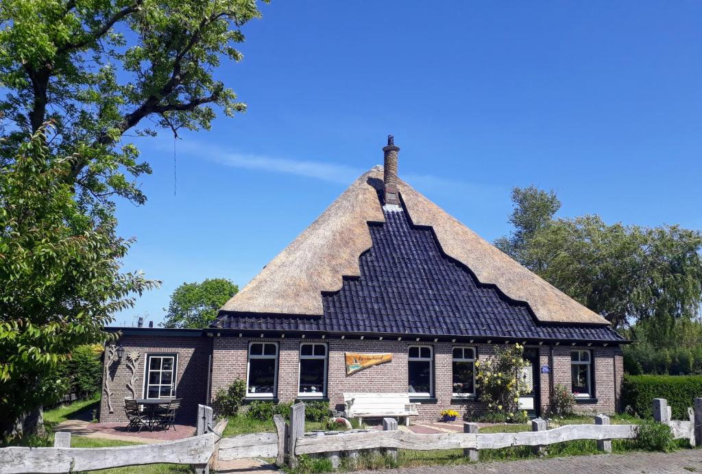 een huis met een rieten dak en een bank voor de deur bij Duinkant in Groet