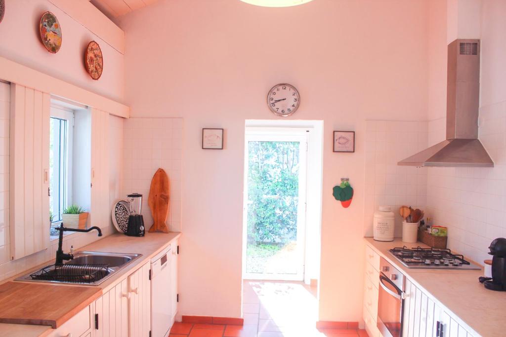 a kitchen with a sink and a clock on the wall at Comporta House in Comporta