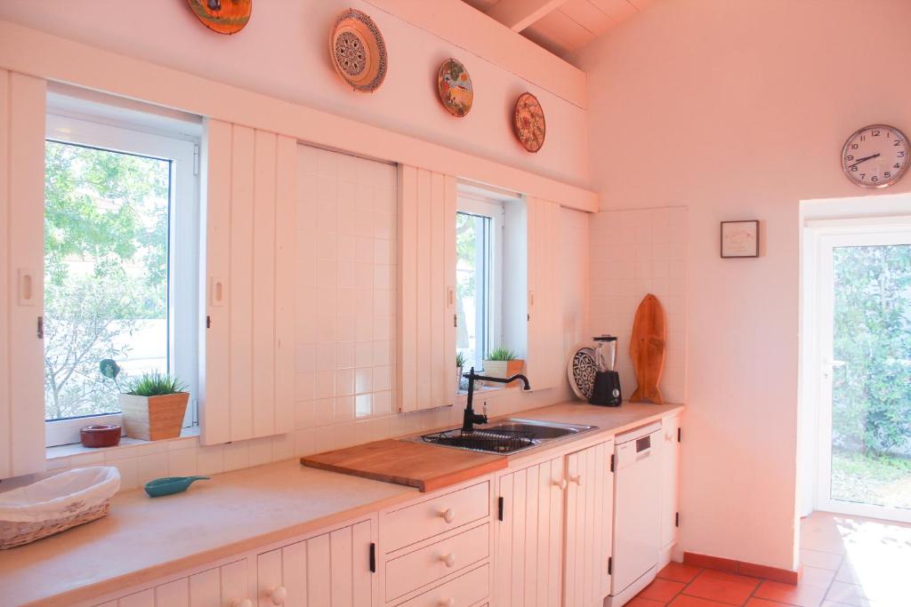 a kitchen with a sink and two windows at Comporta House in Comporta