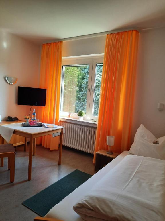 a hotel room with a bed and a desk and window at Gästehaus Bleibergquelle in Velbert