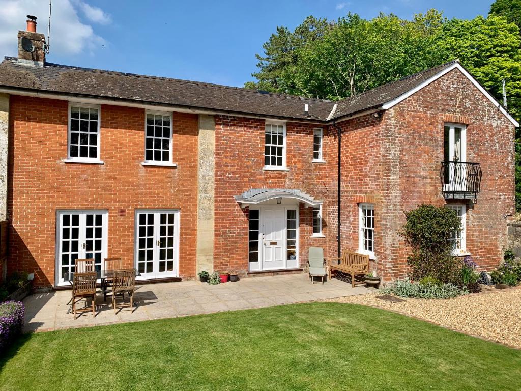 a brick house with a patio and a yard at Glebe House in Barford Saint Martin