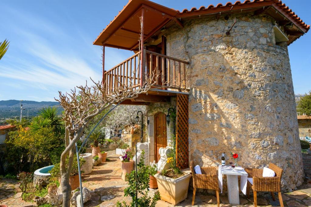 ein Steinhaus mit einem Tisch und Stühlen davor in der Unterkunft Traditional Windmill-Milos in Kroústas