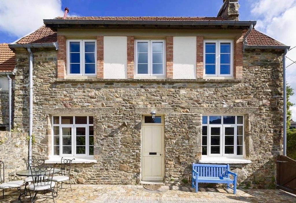 une maison en pierre avec un banc bleu devant elle dans l'établissement Glatigny Farmhouse - close to beach - proche de la plage, à Glatigny