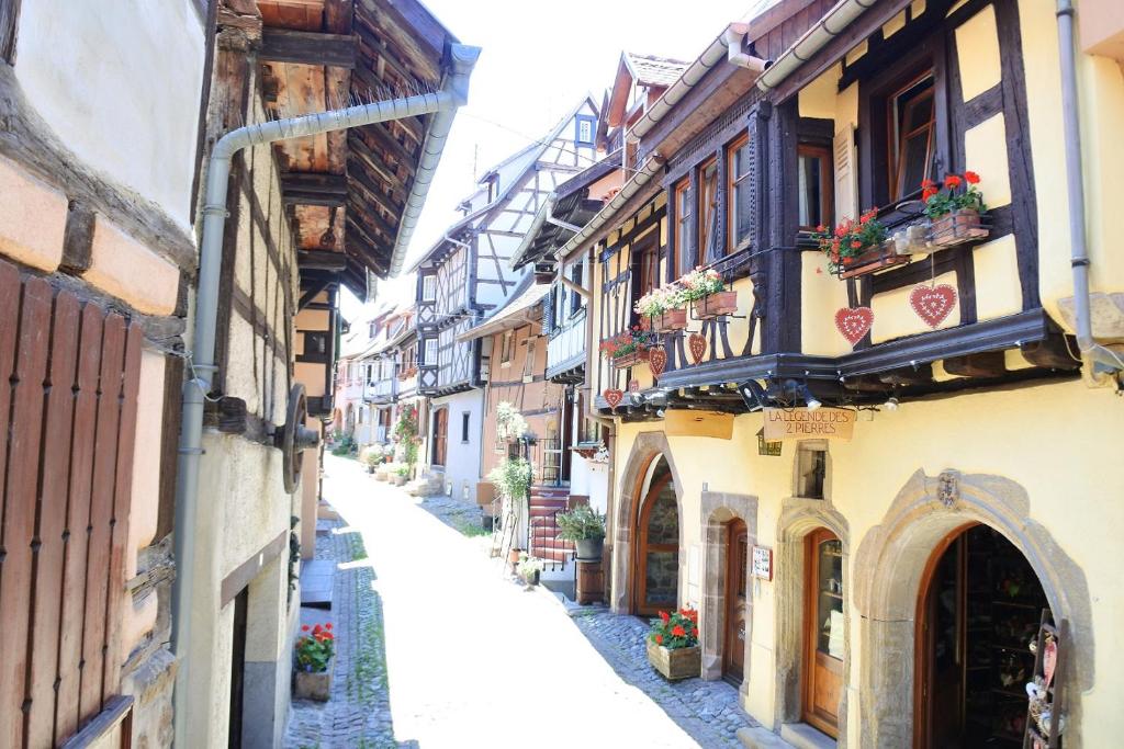 Une allée dans une vieille ville avec des fleurs et des bâtiments dans l'établissement La Légende des 2 Pierres, à Eguisheim
