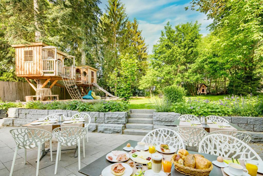 a table and chairs with a tree house in the background at Hotel Knorz in Zirndorf