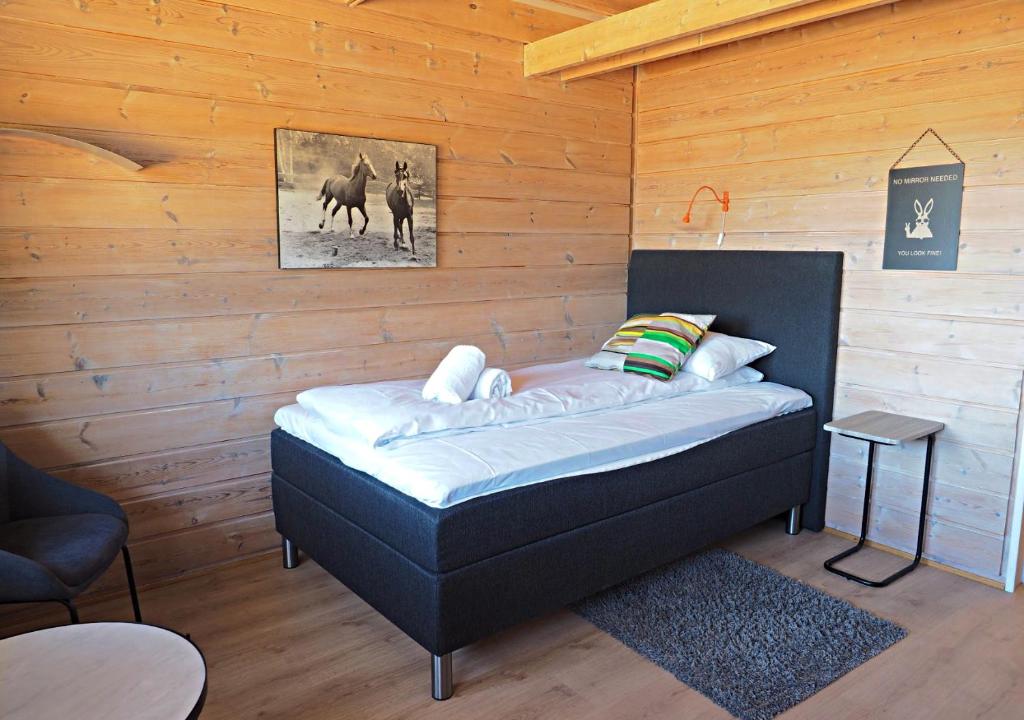 1 dormitorio con 1 cama en una pared de madera en Pan Garden Åmli Hotel, en Åmli