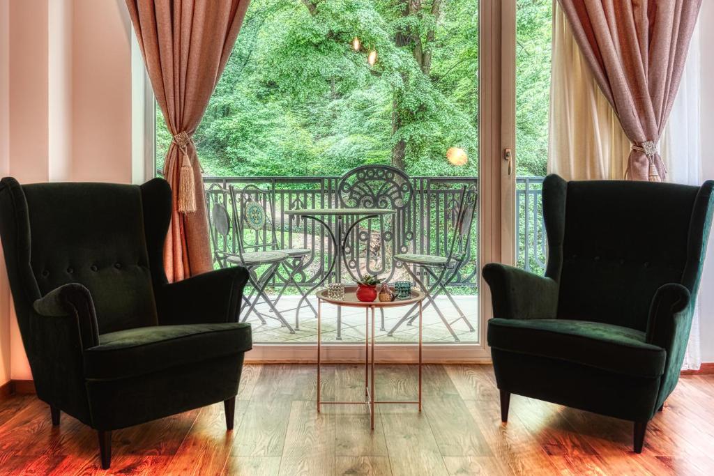 two chairs and a table in front of a large window at Nature Apartment - Minutes Away from the Old Town and AFI Mall in Braşov