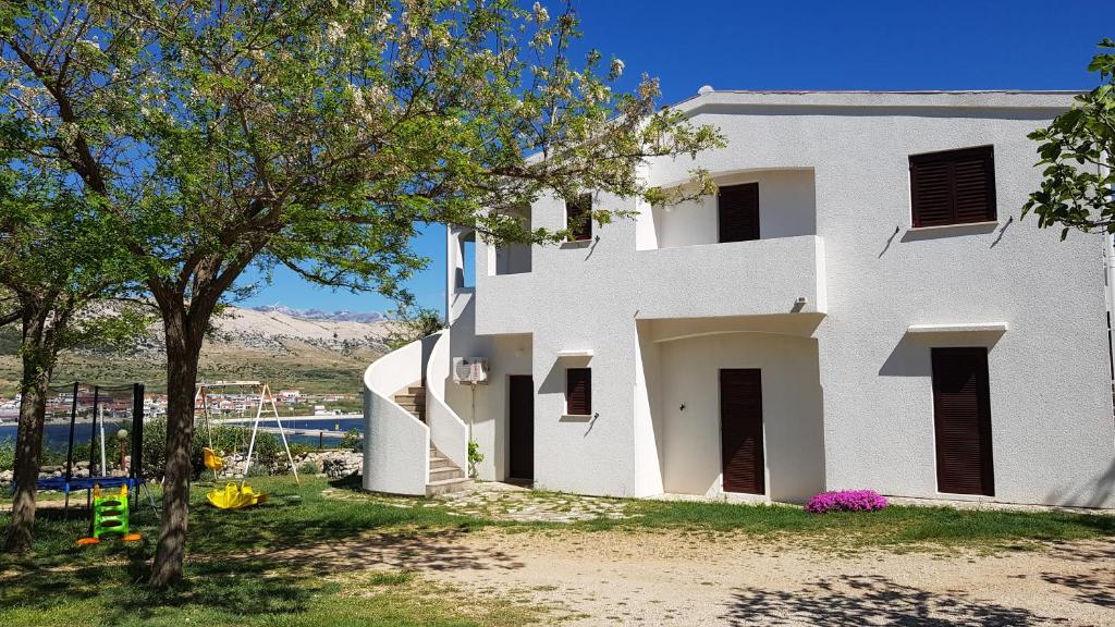 Una casa blanca con un árbol delante. en Apartments Paro, en Pag