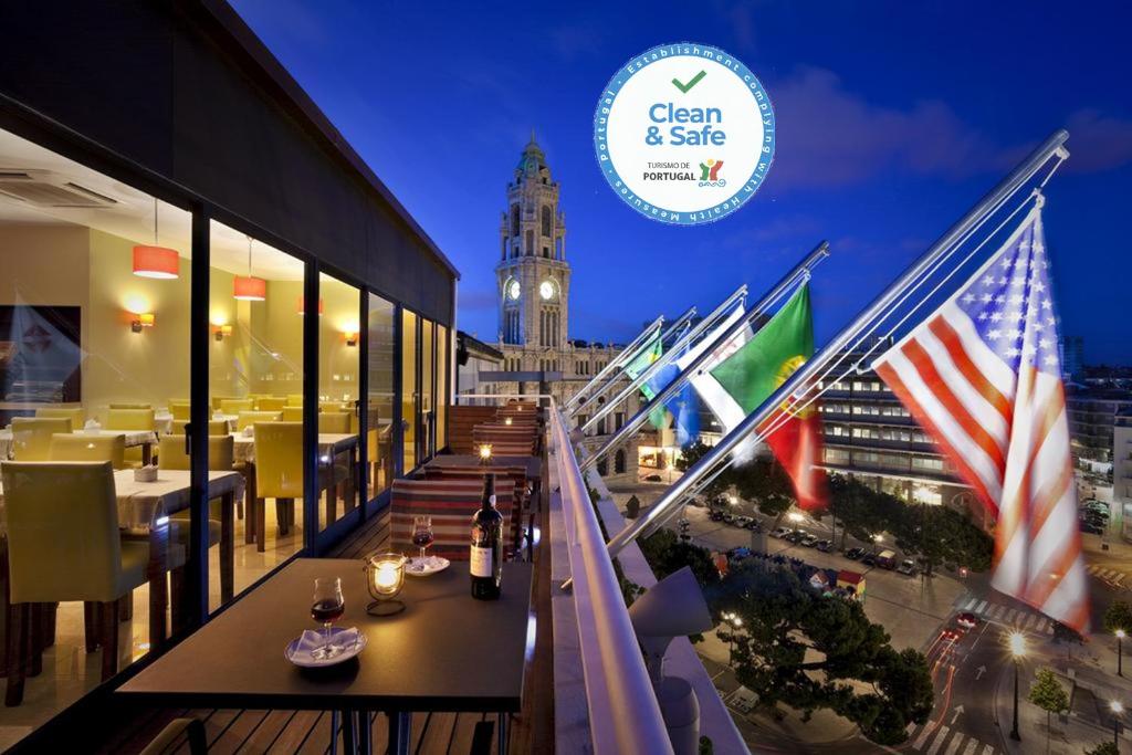 un ristorante con bandiere su un balcone con torre dell'orologio di Vera Cruz Porto Downtown Hotel a Porto