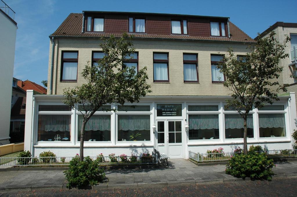 - un grand bâtiment avec des portes et des fenêtres blanches dans l'établissement Pension Haus Weierts, à Norderney