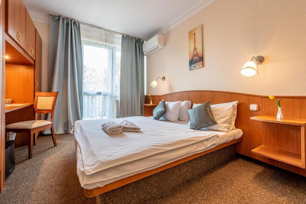 um quarto de hotel com uma cama grande e uma janela em Korona Panzió Budapest em Budapeste