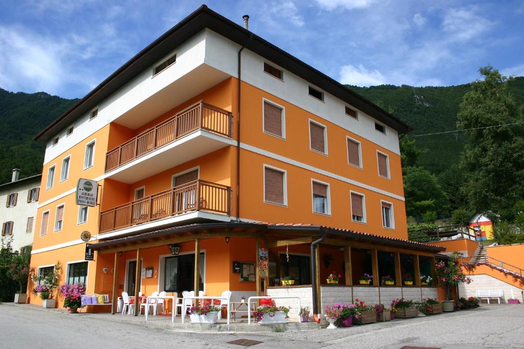 een oranje gebouw met tafels en stoelen ervoor bij Hotel Passo Buole in Vallarsa
